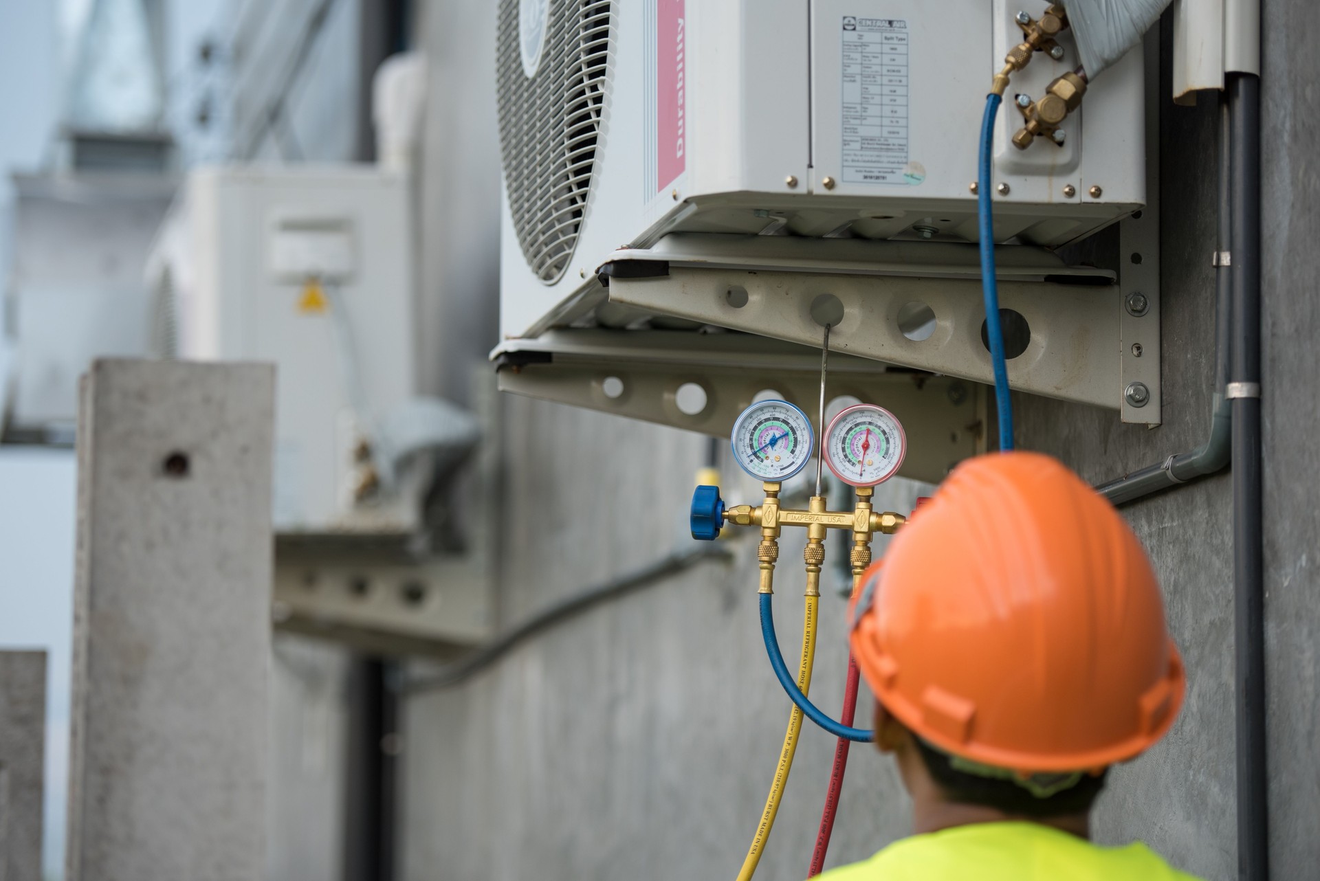 Rear View Of Manual Worker Examining Air Conditioner